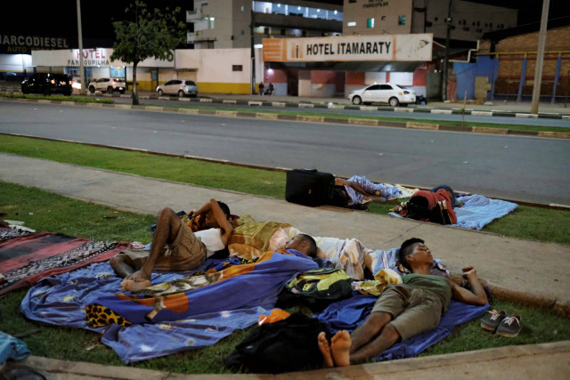 Venezuelan men sleep on the grass in front of interstate Bus Station in Boa Vista