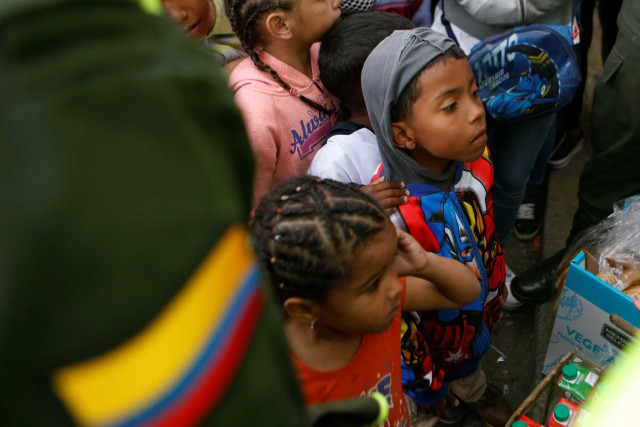 Venezuelan migrant children line up to receive food at a makeshift camp near the transport terminal in Bogota