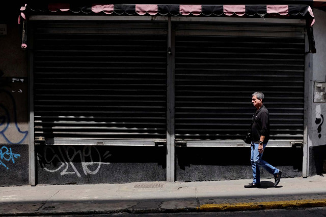 A man walks past closed stores in Caracas