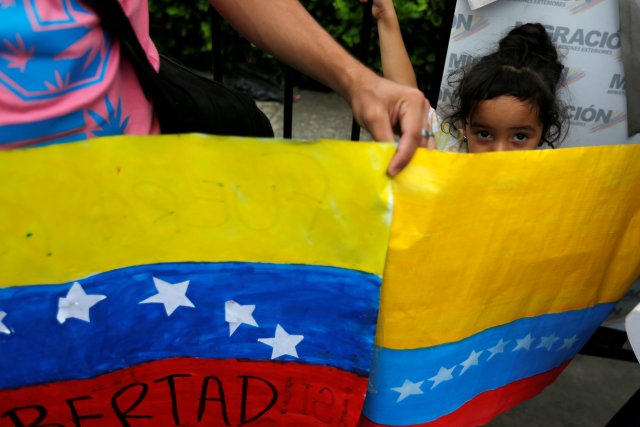 A girl looks over a poster painted with the flag of Venezuela, at the Simon Bolivar international bridge in Cucuta, Colombia