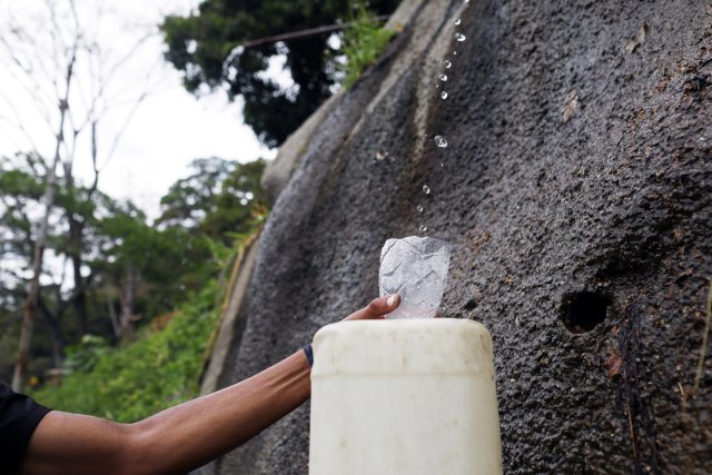A man fills a tank with water coming from the mountain in Caracas