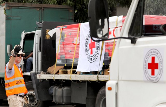 A worker directs trucks with logo of the International Federation of Red Cross and Red Crescent Societies (IFRC) carrying humanitarian aid, at a warehouse where the aid will be stored, in Caracas