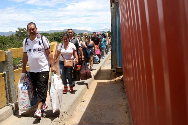 People walk past containers blocking the Colombian-Venezuelan border over the partially opened Simon Bolivar international bridge in San Antonio del Tachira