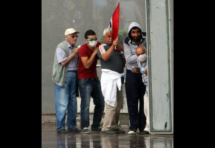 Un grupo de manifestantes se refugia de un cañón de agua durante los enfrentamientos con la policía antidisturbios en Ankara.